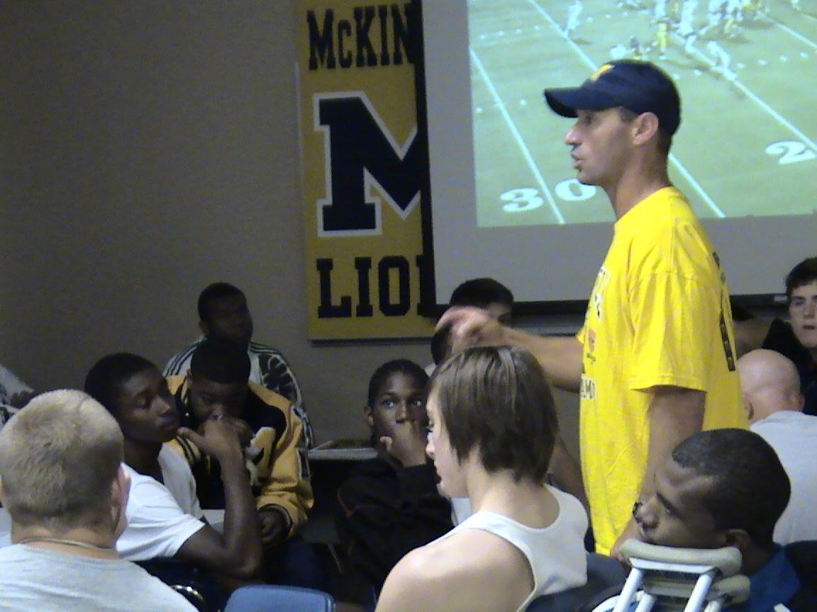 A football coach reviews film with his players.